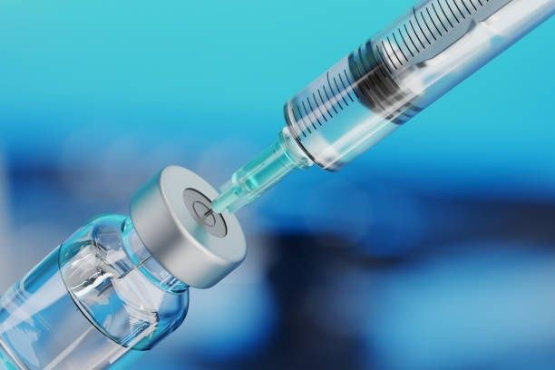 En spruta förs in i gummiproppen på en vaccinflaska